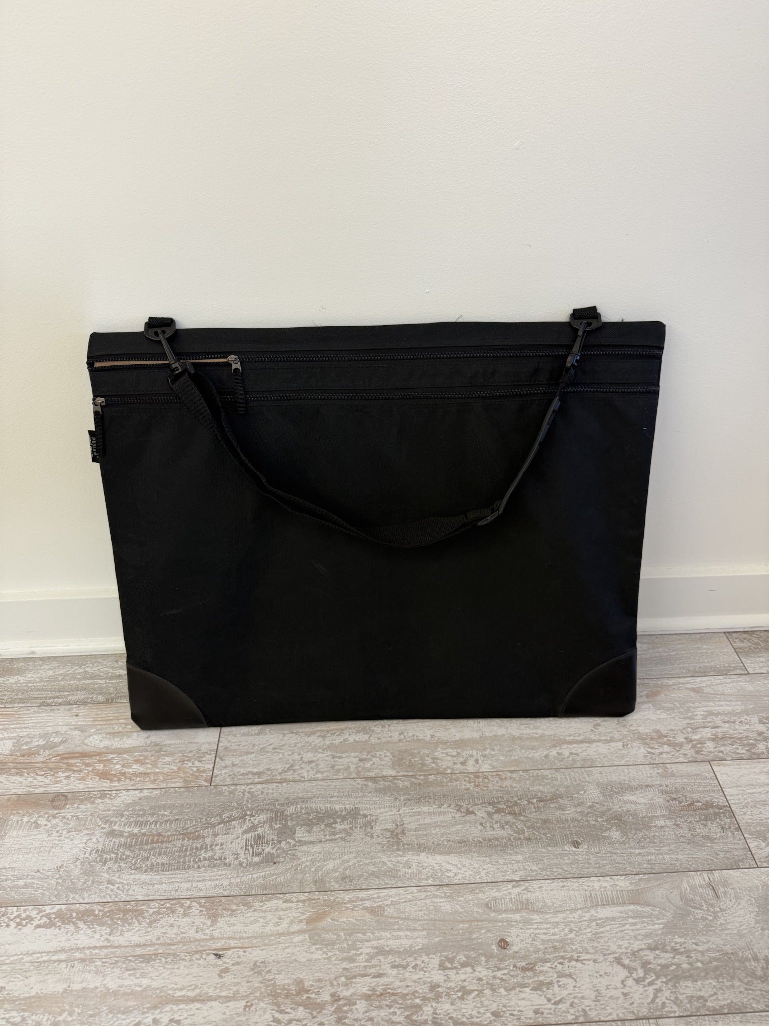 Black soft-sided artist portfolio bag with shoulder strap and zippered front pocket